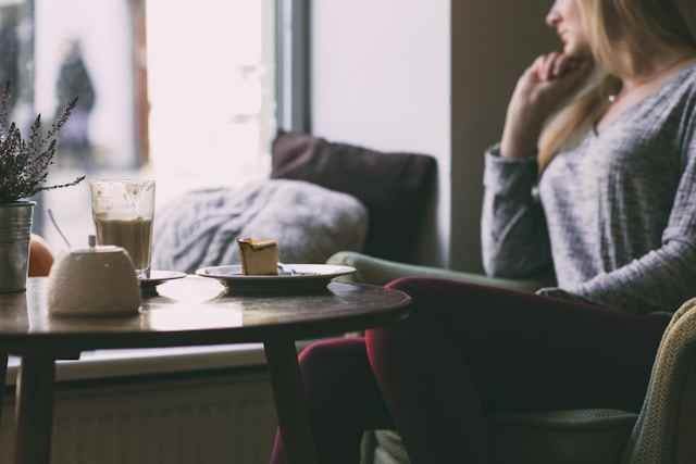 Femme réfléchissant seule dans un café après un diagnostic d’infertilité inexpliquée