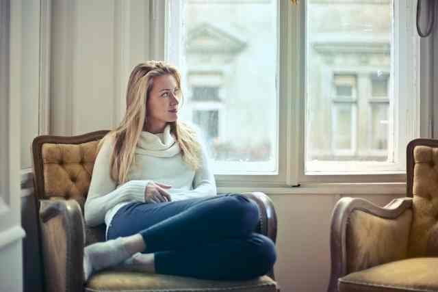 Femme pensive dans un intérieur lumineux se demandant pourquoi je ne tombe pas enceinte alors que j'ovule