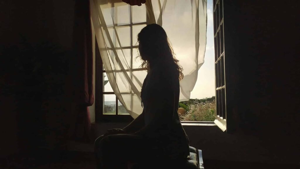 Silhouette de femme assise dans la pénombre illustrant la question pourquoi une FIV peut échouer alors que tout semblait favorable?